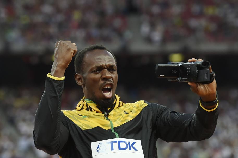 Dopo aver temuto seriamente di perdere il titolo dei 100, Usain Bolt si è presentato sul podio dei Mondiali di Pechino munito di una videocamera con cui ha filmato il pubblico che lo ha applaudito. Il primatista del mondo ha poi ricevuto l&#39;oro dalle mani del presidente uscente della Iaaf, Lamine Diack